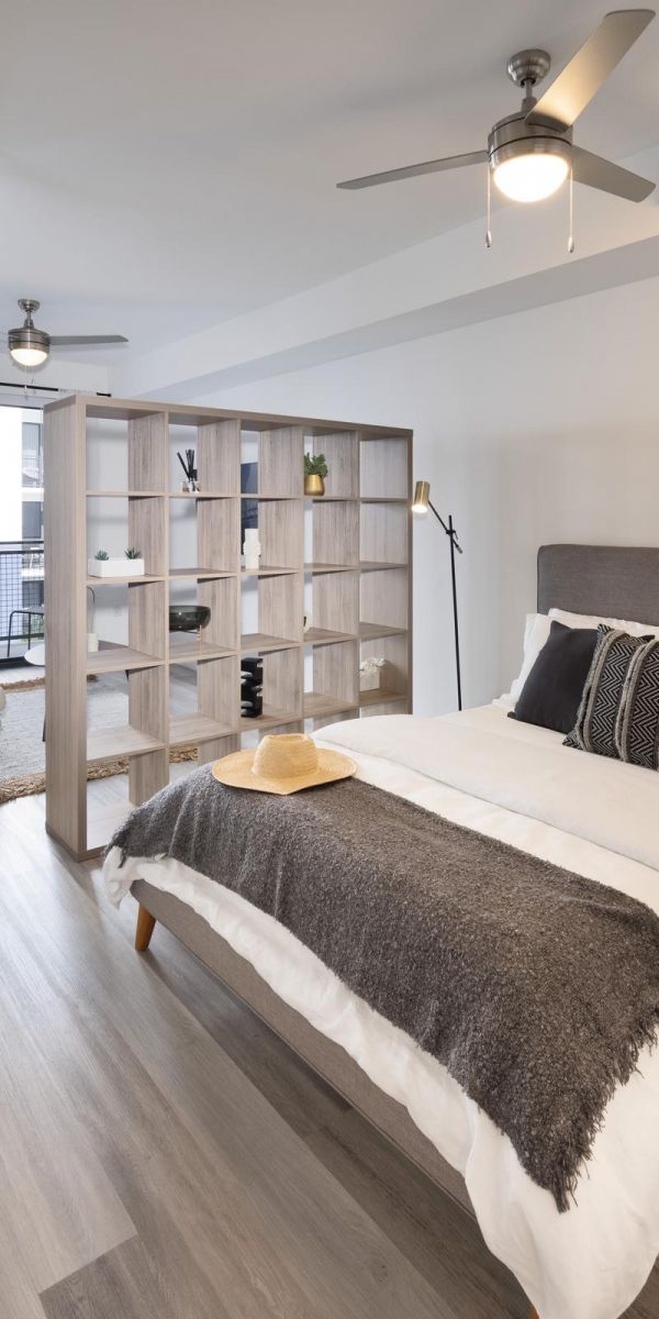 The Upland Modern studio apartment with a bed, room divider, dining area, and light wood flooring.