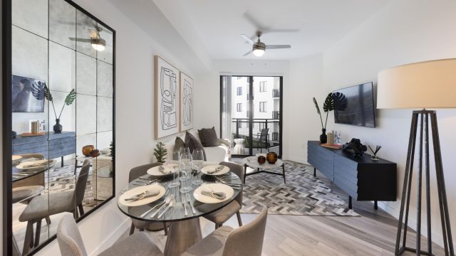 The Upland Modern living and dining area with a round table, chairs, large mirror, artwork, and a balcony view.