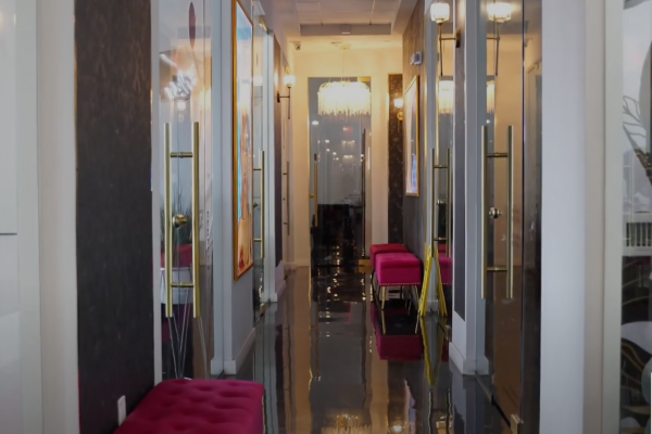 The Upland A reflective hallway with glass doors, pink seating, and a chandelier at the end.